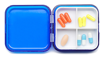 A four-section medicine container opened up showing four types of pills