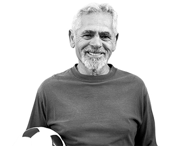 An individual holding a soccer ball smiles