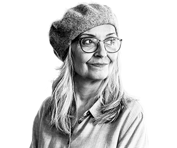 An individual wearing a beanie and glasses looks sideways